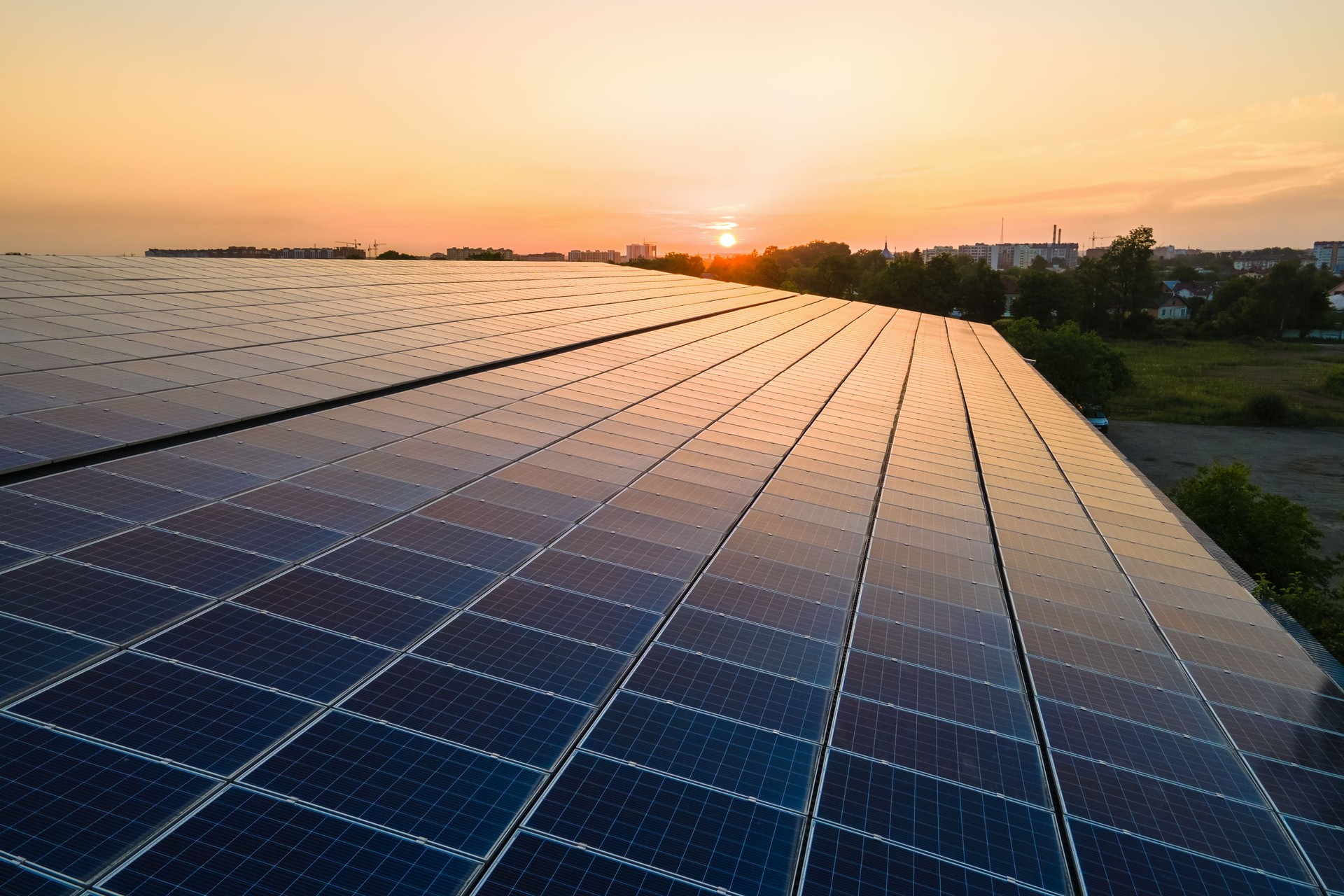 Panneaux solaires photovoltaïques bleus montés sur le toit du bâtiment pour produire de l’électricité écologique propre au coucher du soleil. Concept de production d’énergie renouvelable.