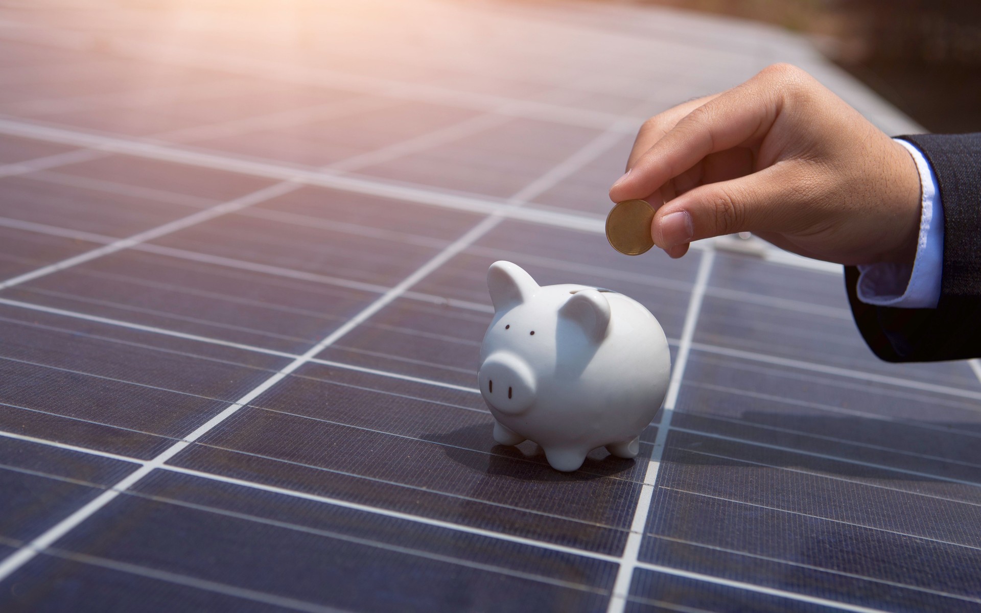 Un homme d’affaires économise des pièces de monnaie sur des panneaux solaires Concept d’investissement utilisant l’énergie des panneaux solaires, les énergies renouvelables, la protection de l’environnement Sources d’énergie renouvelables du